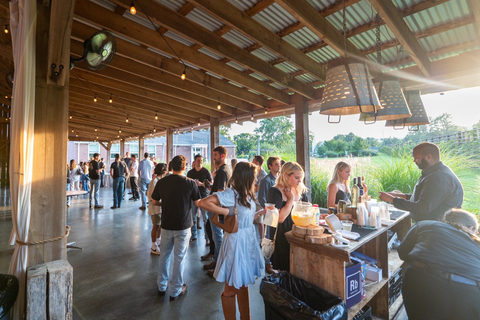 Golden-hour crowd mingling at the bar during Barn after Dark